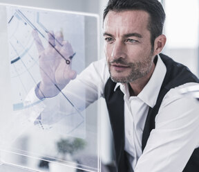 Businessman working in office, using futuristic computer with a transperant screen - UUF15851