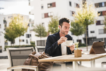 Geschäftsmann sitzt in einem Café, trinkt Kaffee und benutzt sein Smartphone - UUF15874