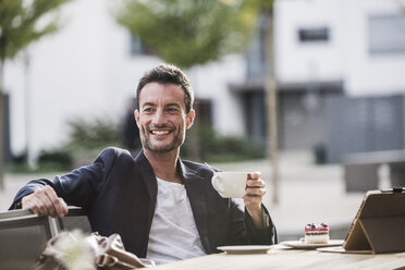 Geschäftsmann sitzt in einem Café, trinkt Kaffee und benutzt sein Smartphone - UUF15880