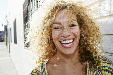 Porträt einer jungen lächelnden Frau mit langem lockigem blondem Haar, die in die Kamera schaut., lizenzfreies Stockfoto