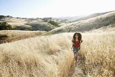 Junge Frau mit lockigem braunem Haar beim Wandern im Stadtpark. - MINF09180