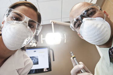 Looking up at a male dentist and a female technician from the viewpoint of a patient. - MINF09190