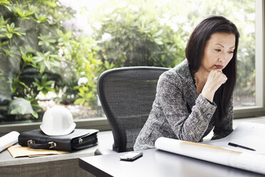 An Asian businesswoman working on architectural plans in her business office. - MINF09195