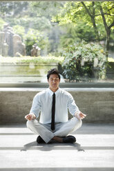 A businessman taking a meditative break in a room full of indoor plants. - MINF09196