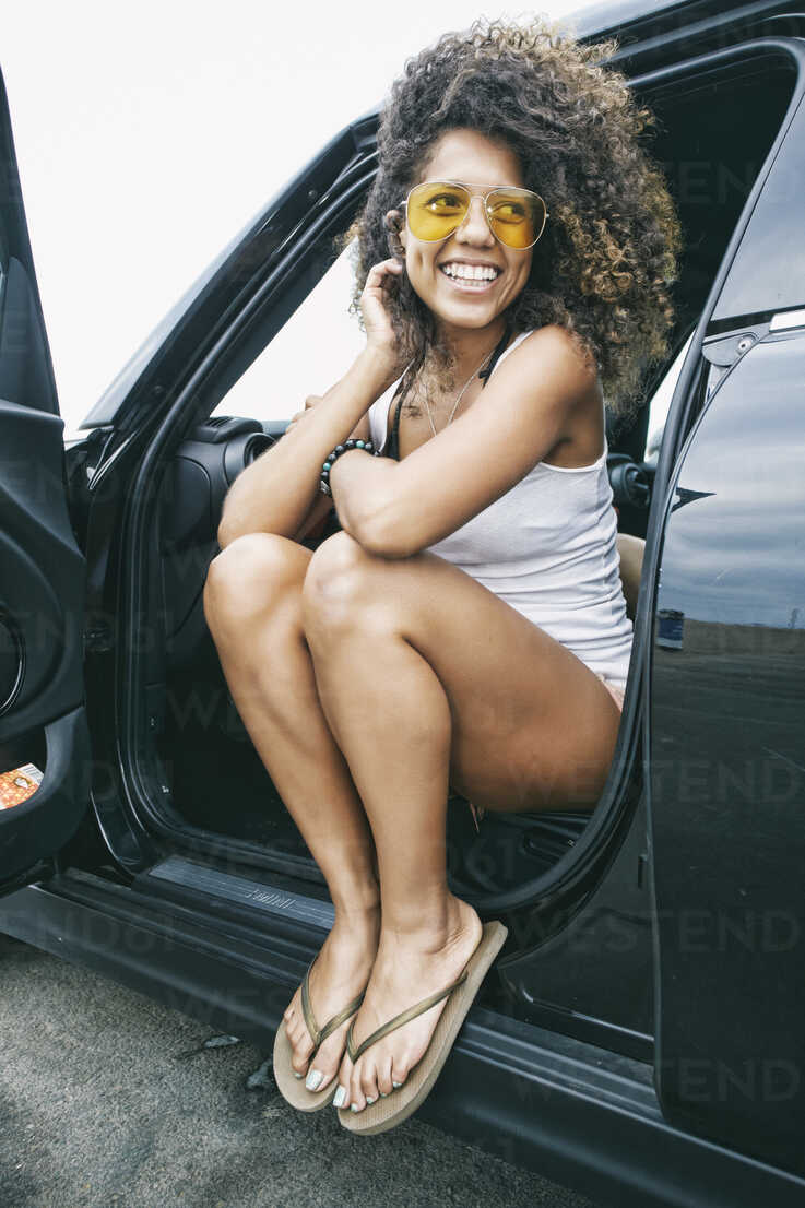 Portrait of smiling young woman wearing sunglasses, white vest and