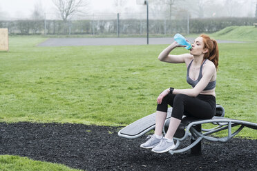 Young woman with long red hair wearing sports kit, exercising outdoors. - MINF09335