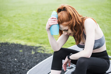 Junge Frau mit langen roten Haaren in Sportklamotten, die im Freien trainiert. - MINF09337