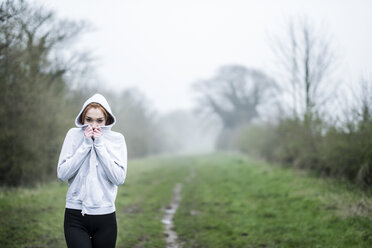 Junge Frau mit langen roten Haaren in Sportkleidung, die im Freien trainiert und in die Kamera schaut. - MINF09342