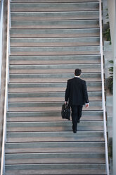 Blick von oben auf einen Geschäftsmann, der in der Lobby eines Konferenzzentrums eine Treppe hinaufgeht. - MINF09369