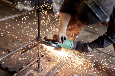 Ein Metallhandwerker bei der Arbeit mit einem Winkelschleifer, der einen Metallzaun bearbeitet. - MINF09407