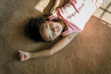 Girl laying on living room carpet in the sunlight - MINF09417