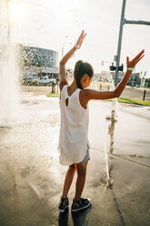 Girl playing in public fountain in summer - MINF09426