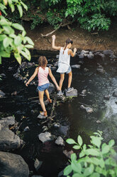 Girls using stones to cross creek - MINF09442