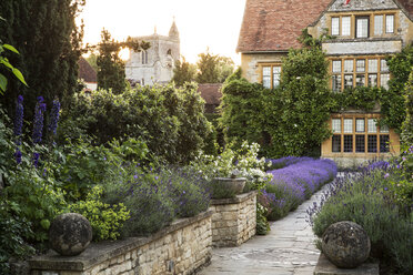 Blick auf das historische Herrenhaus über einen ummauerten Garten mit Weg und Blumenbeeten. - MINF09481