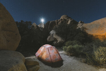 Illuminated tent on desert against rocks at Joshua Tree National Park during night - CAVF53209