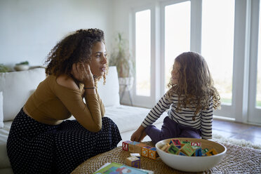 Mother and daughter talking while playing with toy blocks at home - CAVF53210