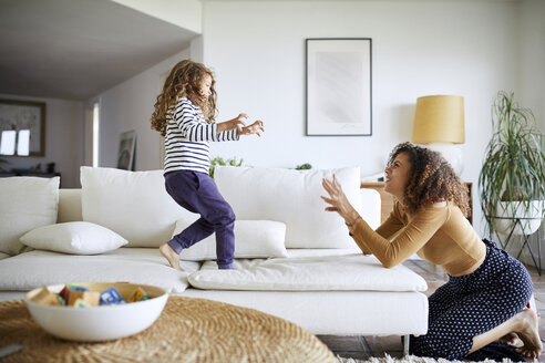 Seitenansicht einer glücklichen Mutter, die mit ihrer Tochter im Wohnzimmer spielt - CAVF53221
