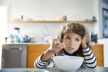 Girl looking away while eating food on table at home - CAVF53231