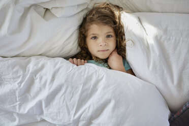 Hochformatiges Porträt eines Mädchens, das zu Hause auf dem Bett liegt - CAVF53236
