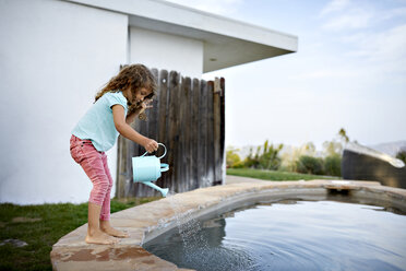 Side view of girl pouring water in swimming pool against sky - CAVF53249