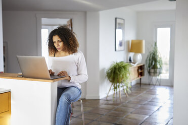 Woman using laptop computer on table at home - CAVF53250