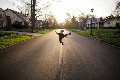 In voller Länge von spielerischen Jungen treten in der Luft beim Üben Karate auf der Straße bei Sonnenuntergang - CAVF53294