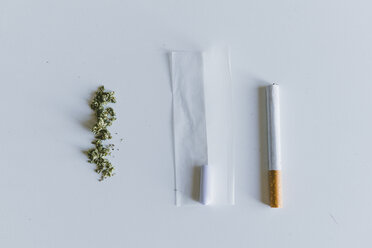 Overhead-Ansicht von Marihuana Joints und Zigarette mit Papier auf weißem Tisch - CAVF53320