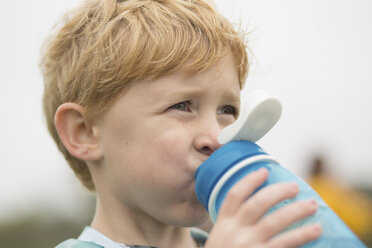 Close-up of boy looking away while drinking water against sky - CAVF53338