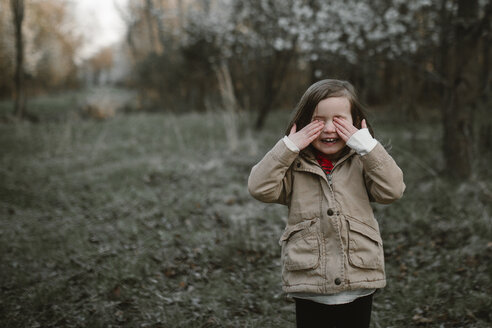 Ein weinendes Mädchen steht auf einer Wiese im Wald im Winter - CAVF53354