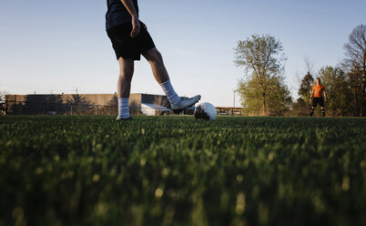 Niedriger Ausschnitt eines Mannes, der mit einem männlichen Freund auf einer Wiese gegen den klaren Himmel im Park Fußball spielt - CAVF53361