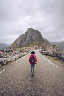 Norwegen, Lofoten, Hamnoy, Rückenansicht eines Mannes mit Rucksack, der auf einer leeren Straße steht - RSGF00067