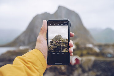 Norwegen, Lofoten, Hamnoy, Hand hält Smartphone zum Fotografieren - RSGF00070