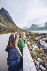 Norwegen, Senja, zwei junge Frauen stehen am Straßenrand und betrachten die Aussicht - RSGF00074