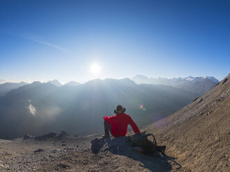 Border region Italy Switzerland, senior man having a break from hiking in mountain landscape at Piz Umbrail - LAF02144