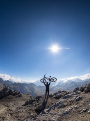 Border region Italy Switzerland, cheering man with mountainbike on peak of Piz Umbrail - LAF02152