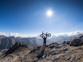 Grenzregion Italien Schweiz, jubelnder Mann mit Mountainbike auf dem Gipfel des Piz Umbrail - LAF02153