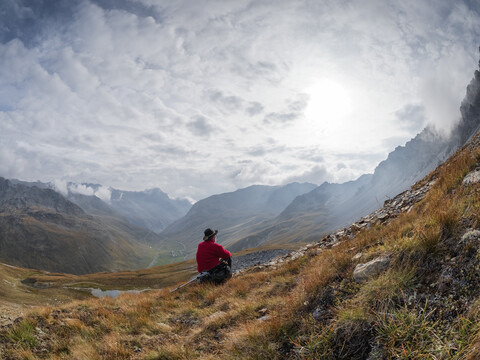 Grenzregion Italien Schweiz, älterer Mann, der eine Pause vom Wandern in der Berglandschaft am Piz Umbrail macht, lizenzfreies Stockfoto