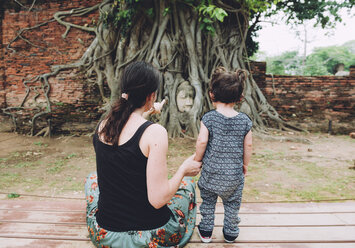 Thailand, Ayutthaya, Mutter und Tochter besuchen den Buddha-Kopf zwischen Baumwurzeln im Wat Mahathat - GEMF02463