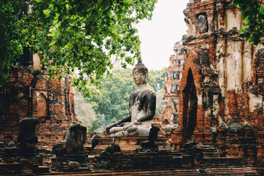 Thailand, Ayutthaya, Buddha-Statue umgeben von Backsteinpagoden im Wat Mahathat - GEMF02469