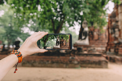 Thailand, Ayutthaya, Frau beim Fotografieren einer Buddha-Statue im Wat Mahathat, lizenzfreies Stockfoto