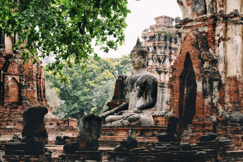 Thailand, Ayutthaya, Buddha-Statue umgeben von Backsteinpagoden im Wat Mahathat - GEMF02484