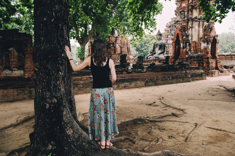 Thailand, Ayutthaya, Woman looking at a Buddha statue at Wat Mahathat stock photo