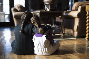 Rückansicht von Schwestern, die zu Hause auf dem Boden sitzen - CAVF53414