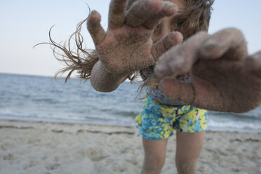Portrait of girl with messy hands standing at beach against clear sky - CAVF53416