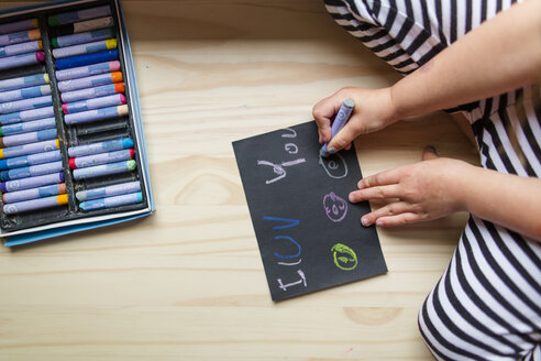 Mittelteil eines Mädchens, das mit bunten Buntstiften auf Papier zeichnet, während es zu Hause kniet - CAVF53479