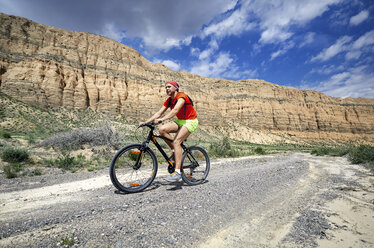 Seitenansicht eines Wanderers auf dem Fahrrad in der Wüste gegen Felsformationen - CAVF53497