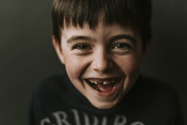 Close-up portrait of happy boy standing against wall - CAVF53516