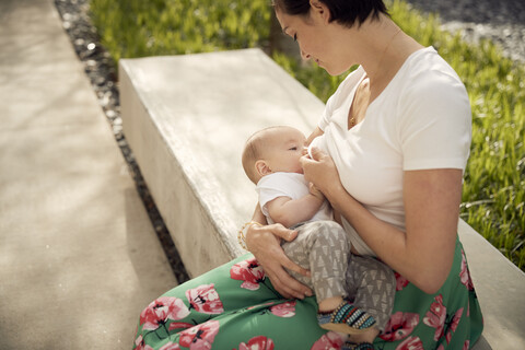 Hoher Blickwinkel der Mutter, die ihre Tochter stillt, während sie auf dem Sitz sitzt, lizenzfreies Stockfoto