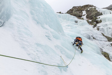 Low angle view of backpacker ice climbing at White Mountains during winter - CAVF53539