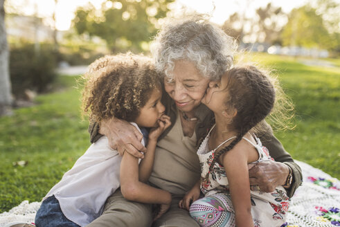 Enkelkinder mit Großmutter auf Picknickdecke im Park - CAVF53555